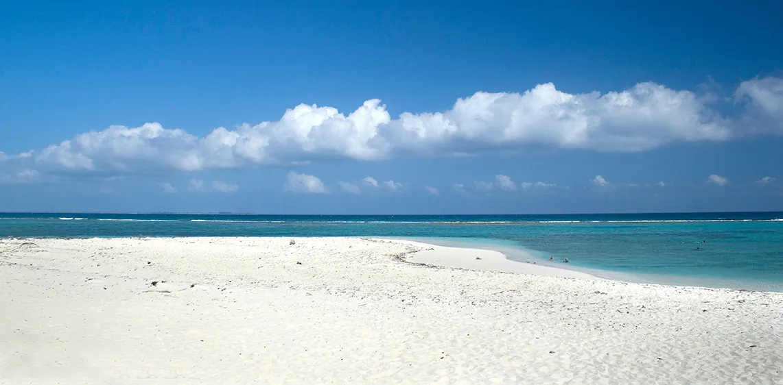 white sandy beach with blue sky and white clouds